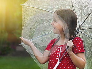 Child wearing polka dots dress under umbrella in rainy day