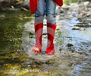 Child wearing red rain boots jumping. Close up