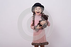 Child wearing retro hat and holding vintage teddy bear.