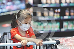 child wearing surgical face mask buying fruit in supermarket