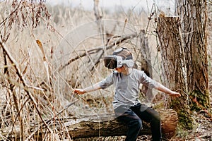 Child wearing virtual reality goggles outside in spring nature in forest