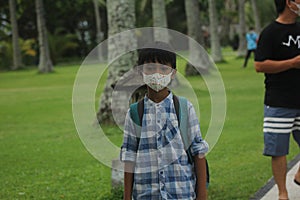 a child wears a medical mask and adheres to health protocols in a hotel garden, to protect him from disease, virus, Covit-19