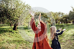 Child whirling, dancing plays on the meadow. Girl having fun with bubbles.