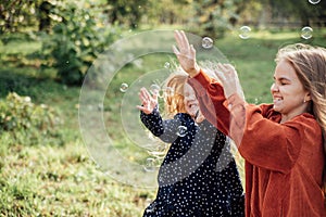Child whirling, dancing plays on the meadow. Girl having fun with bubbles.