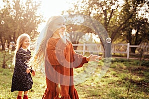 Child whirling, dancing plays on the meadow. Girl having fun with bubbles.