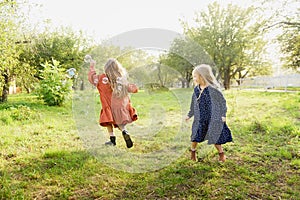 Child whirling, dancing plays on the meadow. Girl having fun with bubbles.