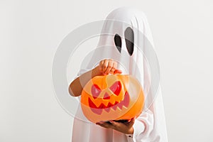 Child with white dressed costume halloween ghost scary he holding orange pumpkin ghost on hand