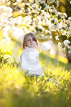 Child in white sweater and jeans, spring flowers