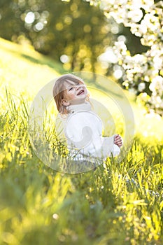 Child in white sweater and jeans, spring flowers