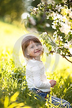 Child in white sweater and jeans, spring flowers
