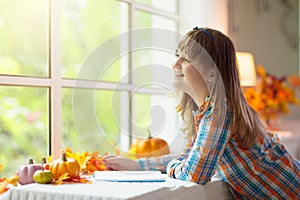 Child at window in autumn. Kids at home in fall