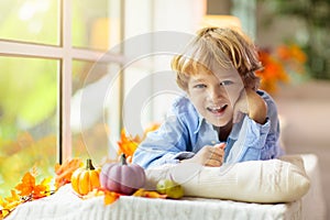 Child at window in autumn. Kids at home in fall