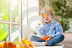 Child at window in autumn. Kids at home in fall