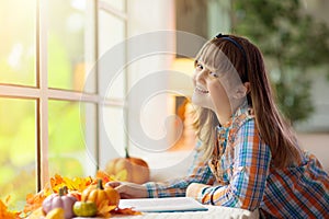 Child at window in autumn. Kids at home in fall