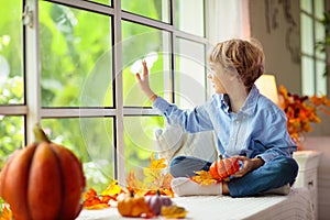 Child at window in autumn. Kids at home in fall