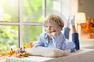 Child at window in autumn. Kids at home in fall