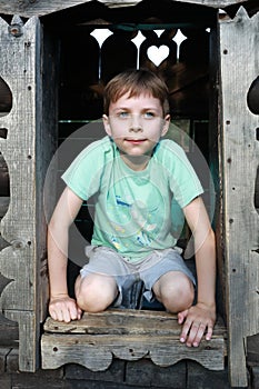 Child in window opening of wooden house