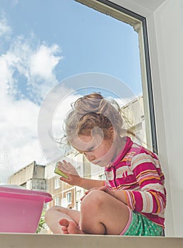 child on the windowsill washes the window, sad, rueful, sorrowful, mournful, sorry, unhappy