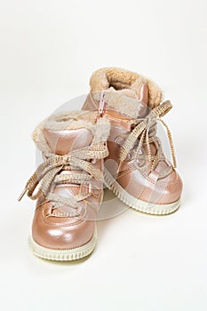 Child winter boots with laces and fur for girls, artificial pink leather and lurex laces, vertical photo. Beautiful shoes for a