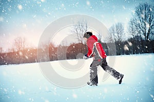 Child in winter clothes playing with snowballs