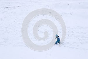 Child with winter clothes walking in a snowfield