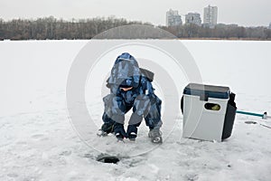 Child on winter fishing. Boy is fishing on an icebound river. Little fisherman. photo