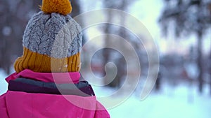 Child in the winter in the forest. Yellow pompom on a girl's hat.