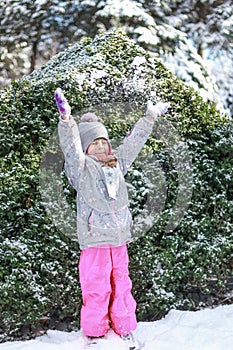 A child in a winter park throws snow over his head and blinks photo