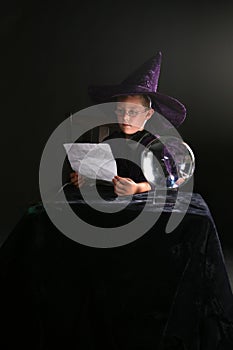 Child in wizard costume consulting his spell