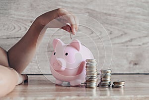 Child woman hand putting money coin into piggy bank for saving money for education study or investment , Stack coins Save money