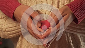 Child and woman hands holding toy heart, concept of parental love and care