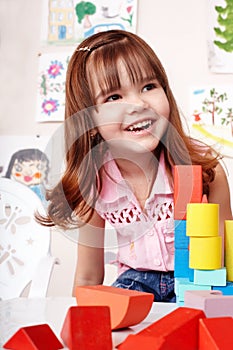 Child with wood block in play room.
