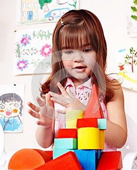 Child with wood block in play room.