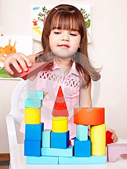 Child with wood block in play room.