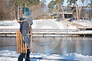 Child with a wooden sled in park a winters day