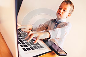 Child working with his computer in his business, concentrated typing to succeed, funny image