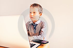 Child working with his computer in his business, concentrated typing to succeed, funny image