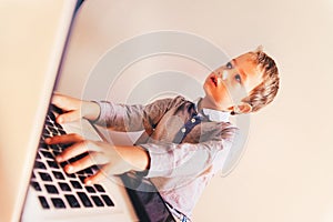 Child working with his computer in his business, concentrated typing to succeed, funny image