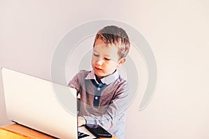 Child working with his computer in his business, concentrated typing to succeed, funny image