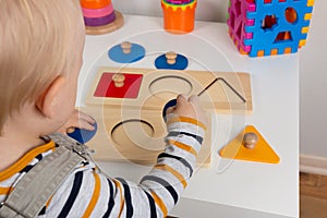 Child works with Montessori material for fine motor skills, sensory play. Playing children with geometry figures
