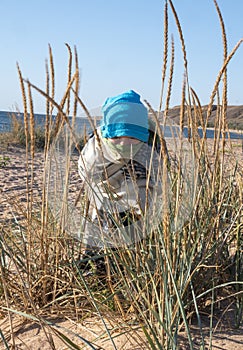 Child wrapped in a blanket on the beach against the sea. The child hid in one eye