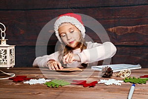 Child writes letter to Santa Claus . Funny girl in Santa hat writes letter to Santa at home