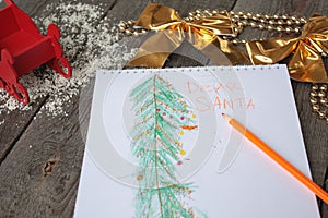 Child writes letter to Santa and draw a Christmas tree.