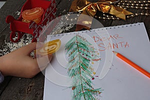 Child writes letter to Santa and draw a Christmas tree.