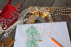 Child writes letter to Santa and draw a Christmas tree.