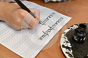 The child writes the word  `calligraphy` with a fountain pen. The Russian text - a calligraphy