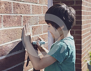 Child writing with chalk colour on the brick wall, Active kid drawing with chalk on wall with bright light on spring or Summer,
