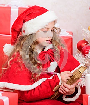 Child writing letter to santa claus. Dear santa. Girl little cute child hold pen and paper near christmas tree. Believe