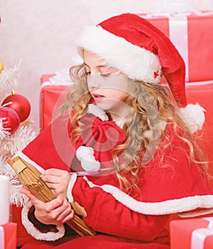 Child writing letter to santa claus. Dear santa. Girl little cute child hold pen and paper near christmas tree. Believe