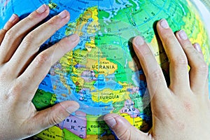 child& x27;s hand on a globe circling ukraine in spanish & x27;ucrania& x27; photo